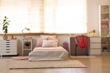 Interior of teenager's room with bed and tables