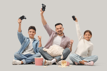 Wall Mural - Happy father with his children playing video game on light background