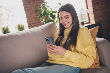 Poster - Portrait of nice teen girl sit couch hold device relax wear yellow clothes modern interior flat indoors