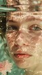 © Infinity - Close-up portrait of a woman underwater, looking at the camera, with a pink flower behind her.