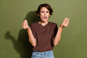 Poster - Portrait of disappointed irritated woman with short hair wear oversize t-shirt raising hadns up argue isolated on green color background