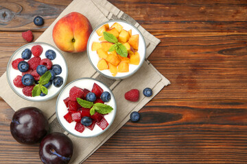 Sticker - Tasty yogurt with fresh berries, fruits and mint in glasses on wooden table, flat lay. Space for text