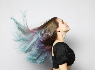 Young woman with multi-colored curly hair shaking her hair, wind in her hair.