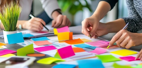 Poster - Closeup of hands working on a sticky note brainstorming session on a table.