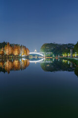 Wall Mural - Night view of red foliage of larch by the lake in City Park