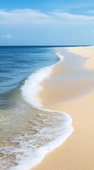 Wall Mural - A wave gently laps the shore of a sandy beach with clear blue water and a blue sky.