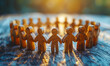 © Bartek - Wooden Figures Holding Hands in a Circle Symbolizing Teamwork and Unity on Rustic Wooden Table, Backlit by Warm Sunset, Concept of Cooperation, Community, Support, and Togetherness