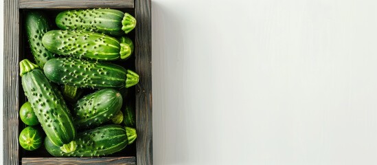 Sticker - Fresh cucumbers in a wooden box set against a white background Top view Copy space