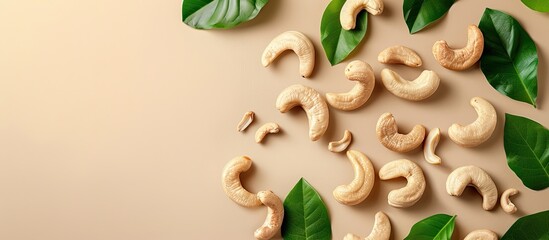 Poster - Delicious cashew nuts and green leaves on a light brown background top view Copyspace available