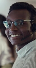Poster - Black man, face and customer service in office, night and communication for tech support and talking. Dark, representative and telemarketing with glasses, advice and consultation in call centre