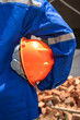 © Nattawit - Action of a house builder worker in blue coverall uniform and holding an orange safety hardhat is standing in front of a building house. Ready to working in construction industrial concept scene.