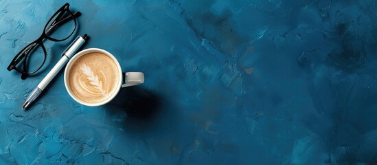 Wall Mural - On a blue background there is a pen glasses and a cup of coffee Top view area for an inscription business concept. with copy space image. Place for adding text or design