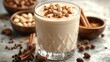 © Iswanto - A glass of creamy milkshake topped with white chocolate chips, cocoa powder and cinnamon sticks, with bowls of ingredients in the background.