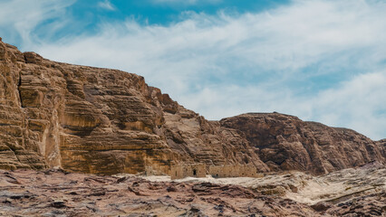 ruins of houses in the desert against the backdrop of high rocky mountains and blue sky with white clouds in Egypt Dahab South Sinai