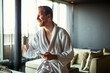 © NDABCREATIVITY - Handsome, muscular, young man drinking his morning coffee in a hotel room