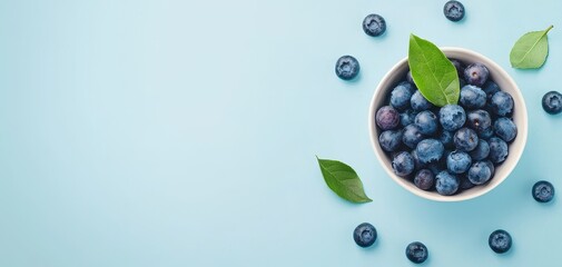 Rustic bowl of blueberries with a green leaf garnish, berries scattered on a light blue background, clean and fresh food presentation