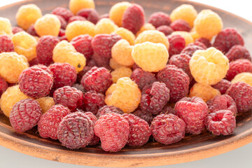 Wall Mural - Fresh raspberry berries on a clay plate, macro, isolated on white background.