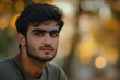 © Mark G - A close-up portrait of a young Indian or Pakistani man wearing a casual t-shirt, with a blurred background.