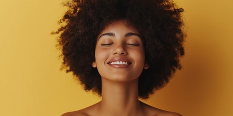 A woman with curly hair is smiling and looking at the camera. She has a relaxed and happy expression on her face