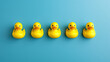 © Oranuch - A charming display of five yellow rubber ducks lined up against a blue background, perfect for playful and cheerful imagery.