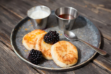 Traditional cheese pancakes with blackberries on rustic table served as tasty and healthy snack delicious homemade cheesecake