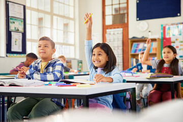 girl raising hand in classroom: she knows the answer!