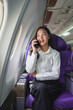 © Phimwilai - Successful Asian businesswoman Business woman working in airplane on laptop computer and looking out the window while talking on the phone Happy online video calling communication concept.