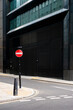 © yaqui_villegas - A street corner featuring a red no entry sign, against a backdrop of dark modern buildings, highlighting the urban landscape and interplay between infrastructure and architecture.
