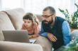 © Anna Lurye - A little girl and her father focus intently on a laptop screen, in a collaborative moment that could involve studying or leisure