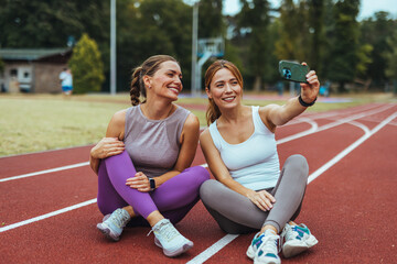 We in on the bestie fitness challenge! Shot of two women taking a selfie while out for a run together. Motivation Concept. Two women in fashionable sports clothes relaxing after training