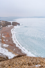 Wall Mural - Mystical winter storm on the shore of a frozen sea with rocky shores. Winter frozen sea and snowstorm. Winter sea fairy tale.