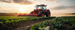 © khonkangrua - A vibrant red tractor actively plows a vast agricultural field at sunrise, showcasing modern farming techniques and machinery.