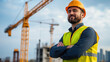 © khonkangrua - Smiling construction worker wearing safety gear, standing confidently at a building site with cranes in the background.