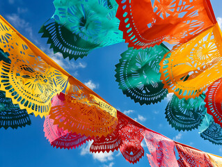 Wall Mural - A colorful array of paper lanterns hang in the sky, creating a festive and lively atmosphere. The bright colors and patterns of the lanterns contrast with the clear blue sky