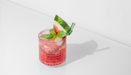 Wall Mural - Glass of refreshing watermelon smoothie with basil, ice on white isolated background with shadow.