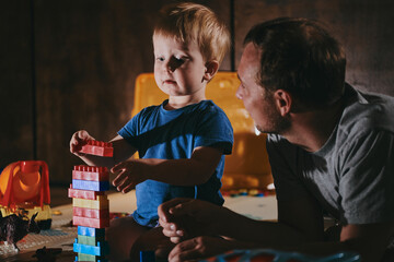 Little boy with his dad playing with toys at home. Happy father and son spending time together