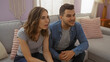 © Krakenimages.com - Couple sitting together on a sofa in a living room, expressing surprise while watching something on a screen indoors