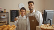 © Krakenimages.com - Man and woman bakers working together in a bakery shop interior standing by the counter with pastries and smiling at the camera