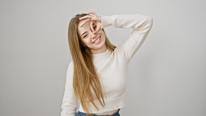 Wall Mural - A joyful young woman with blonde hair making a playful gesture against a white background.