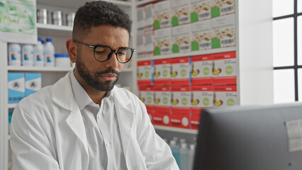 Sticker - African american pharmacist reviewing data on a computer in a modern pharmacy interior