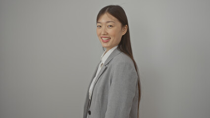 Sticker - Portrait of a young asian woman smiling, dressed in a business suit over isolated white background