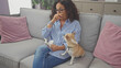 © Krakenimages.com - A middle-aged woman with glasses looks upset on a grey sofa with a chihuahua, indoors, in a living room.