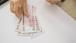 © Krakenimages.com - Adult woman's hands counting saudi riyal banknotes on a white office table