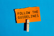 © Emre Akkoyun - Follow the guidelines message written on ripped orange torn paper piece with blue background. Conceptual follow the guidelines symbol. Copy space.