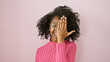 © Krakenimages.com - Happy african woman with curly hair wearing glasses and pink sweater covering one eye with hand against a pink background