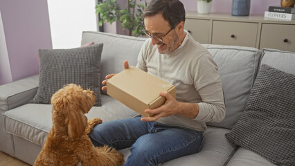 A middle-aged man surprises his poodle with a gift box in a cozy living room setting, expressing joy and companionship.