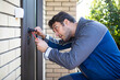 © Vitaliy - Handsome repairman fixing the door on the backyard