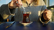 © Krakenimages.com - A woman sweetening her tea at an outdoor cafe with modern attire, capturing a relaxed urban lifestyle.