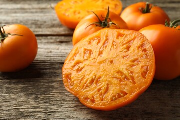 Wall Mural - Cut and whole ripe yellow tomatoes on wooden table, closeup