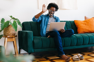 Mature freelancer smiling and waving during a video call from his home office